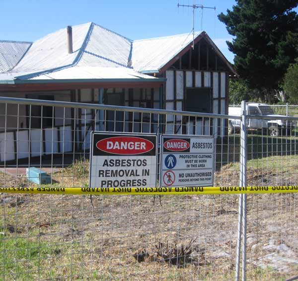 Photo of a Danger sign on a fence surrounding a building before it is demolished